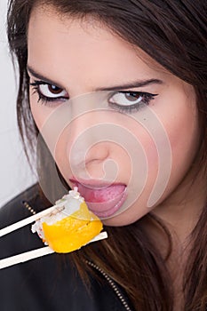 Beautiful young woman eating sushi roll