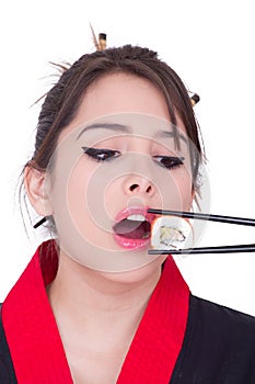 Beautiful young woman eating sushi roll