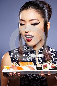 Beautiful young woman eating sushi.