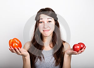 Beautiful young woman eating an vegetables. holding a red pepper and tomato. healthy food - strong teeth and body