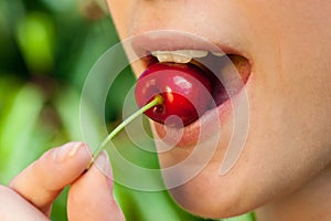 Beautiful young woman eats cherry on plantation