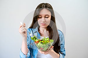 Beautiful young woman eats salad with lettuce, tomato and olives