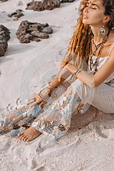 Beautiful young woman in elegant dress lying on sand at the beach at sunset