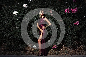 Beautiful young woman in elegant red dress on leaves backdrop.