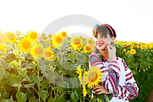 Beautiful young woman in embrodery holding three sunflowers