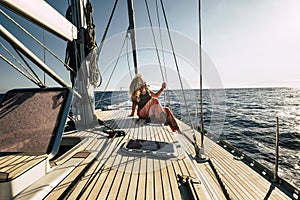 Beautiful young woman enjoy summer holiday vacation or excursion on sailboat with sun and ocean around - people enjoying life and