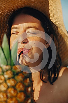 Beautiful young woman enjoying cocktail in pineapple, relaxing in pool on sunny summer vacation. Portrait of girl in hat with
