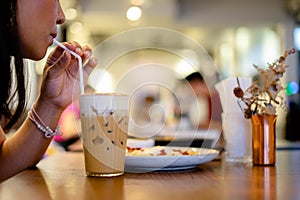 Beautiful young woman enjoying latte coffee in cafe, Woman sucks ice coffee with milk