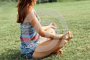 Beautiful young woman enjoying meditation and yoga on green grass in the summer on nature. Beauty woman doing yoga Healthy and yog