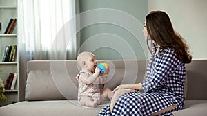 Beautiful young woman enjoying motherhood, playing with active baby, happiness