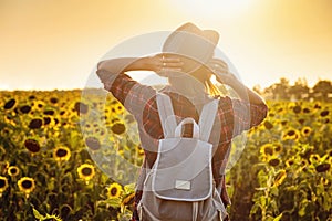 Beautiful young woman enjoying nature on the field of sunflowers at sunset