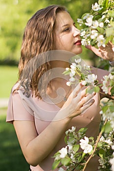 Beautiful young woman enjoying nature in the spring apple orchard, happy Beautiful girl in the garden with flowering