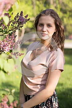 Beautiful young woman enjoying nature in the spring blooming garden, happy Beautiful girl in the garden with lilac