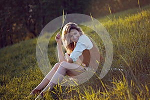 Beautiful young woman enjoying a picnic in nature. Girl sitting on grass, rest, relaxation