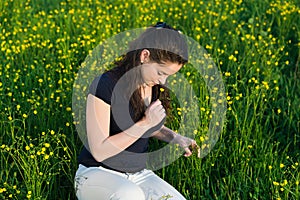 Beautiful young woman enjoying the scent of flowers .