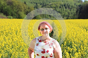 Beautiful young woman enjoying the sun in the meadow with yellow flowers on a warm summer day