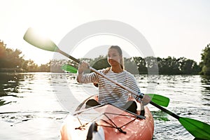 Beautiful young woman enjoying walking by kayak together with her boyfriend on a summer day