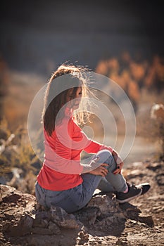 Beautiful young woman enjoys the beauty Valley along the hiking trail posing on the rock on sunny day in Altai