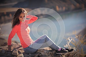 Beautiful young woman enjoys the beauty Valley along the hiking trail posing on the rock on sunny day in Altai