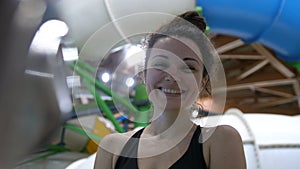 Beautiful young woman enjoys spending time in the water park smiling looking at the camera. slow motion