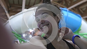 Beautiful young woman enjoys spending time in the water park smiling looking at the camera. slow motion