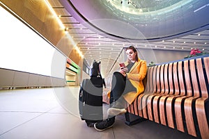 Beautiful young woman European traveler passenger with a smartphone in hand is waiting for departure flight at Istanbul