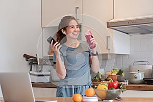 Beautiful young woman in exercise clothes having fun in a cute kitchen at home. Preparing a vegetarian fruit salad or a