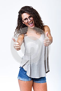 Beautiful young woman expressing happiness with thumb up over white background.