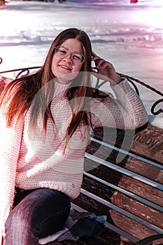 Beautiful young woman in eye glasses knitted sweater in winter park. Cold weather outdoors. Snow Happy smiling portrait