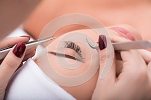 Beautiful young woman during eyelash extension photo