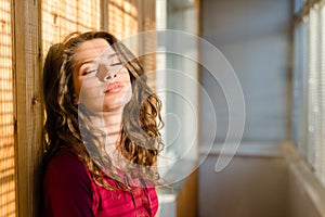 Beautiful young woman eyes closed girl with shadow from window blinds