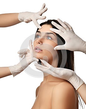 Beautiful young woman face with closed eyes after plastic surgery and doctor hands in medical gloves