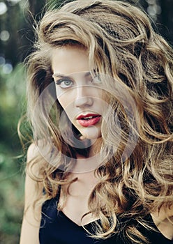 Beautiful young woman face closeup with makeup and brown curly h