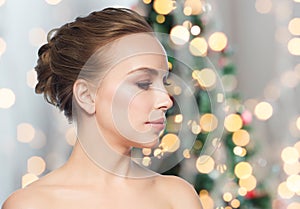 Beautiful young woman face over christmas lights
