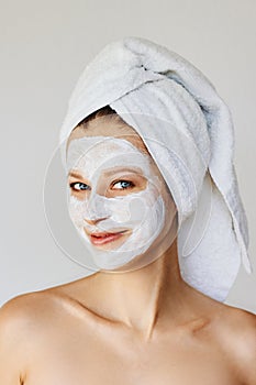 Beautiful young woman with facial mask on her face. Skin care and treatment, spa, natural beauty and cosmetology concept