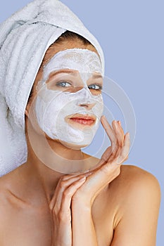 Beautiful young woman with facial mask on her face. Skin care and treatment, spa, natural beauty and cosmetology concept