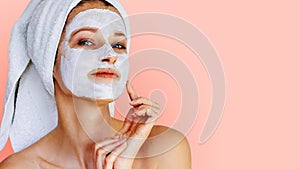 Beautiful young woman with facial mask on her face. Skin care and treatment, spa, natural beauty and cosmetology concept