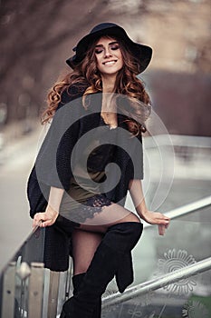 Beautiful young woman in fashion black coat, hat, lace dress an