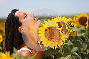 Beautiful young woman feeling the sunflower petals