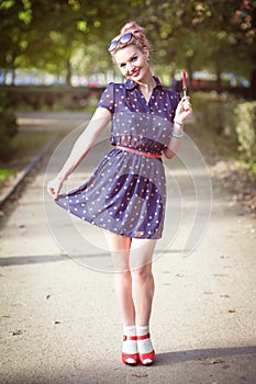 Beautiful young woman in fifties style with braces holding candy