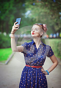 Beautiful young woman in fifties style taking picture of herself