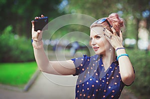 Beautiful young woman in fifties style taking picture of herself