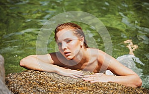Beautiful young woman floating in ocean or sea water, relaxing and taking care of herself. Fashion portrait of graceful