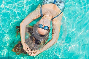 Beautiful young woman floating in pool relaxing Top view. Holiday concept