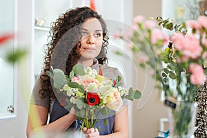 Beautiful young woman florist standing in flower shop