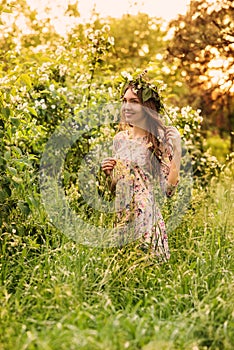 Beautiful young woman in a flower wreath in the park