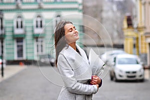 Beautiful young woman with flowers bouquet at city street. Spring portrait of pretty female