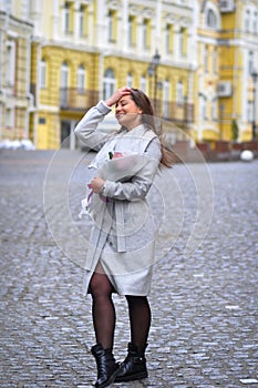 Beautiful young woman with flowers bouquet at city street. Spring portrait of pretty female