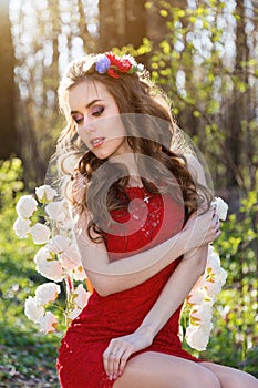 Beautiful young woman with flowers in her hair in the woods