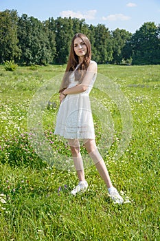 Beautiful young woman in a flowery meadow in a white dress